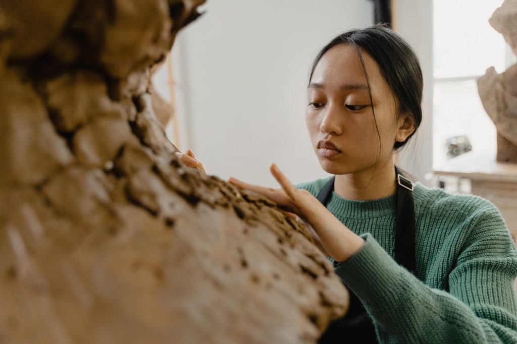 Young woman crafting a clay sculpture with precision in an artist studio.