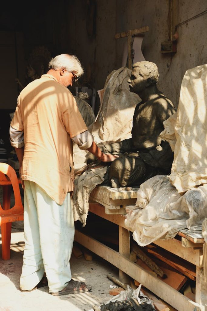 Artist skillfully sculpts a clay statue in a sunlit Kolkata workshop, showcasing traditional craftsmanship.